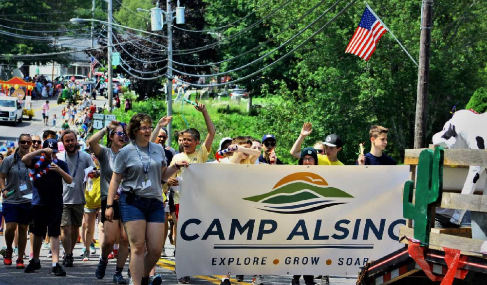 Camp Alsing campers in a parade with large banner